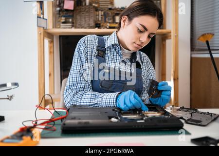 Service woman holds a laptop cooling fan for a repair and cleaning. Technician fix and install to laptop computer. Stock Photo