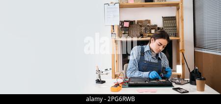 Repairman woman disassembling laptop motherboard and cooler fan. Engineer fixing broken computer at service. Electronic repair shop, technology Stock Photo