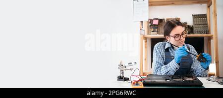 Female repairman working in technical support fixing laptop computer fan, clean it with brush. Copy space. Stock Photo