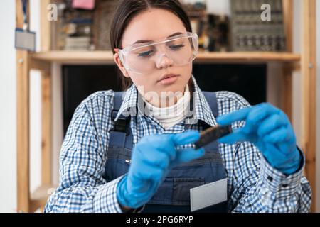 Engineer repairs laptop support fixing notebook computer. IT woman installs equipment CPU, RAM, DDR3. Repairing computer concept. Stock Photo
