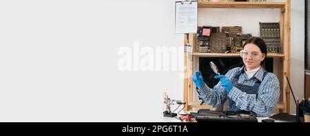 Engineer repairs laptop support fixing notebook computer. IT woman using magnifying glass looking on computer CPU in service center. Stock Photo