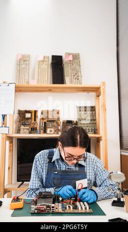 Computer master checks the electronic motherboard and performs electrical measurements. Electronics repair service. Multimeter measuring instrument. Stock Photo