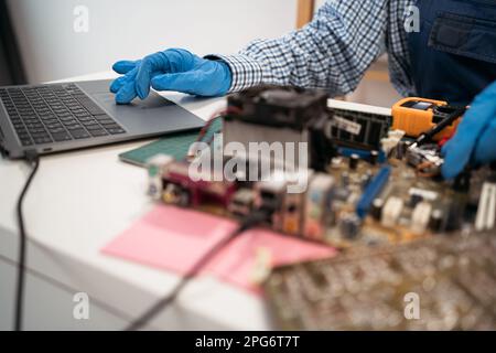 Hands of young woman typing while holding part of hardware during computer repairing work. Stock Photo