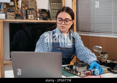 Technician repair. Broken computer motherboard. Electronic pc parts. Motherboard analysis using online video. Stock Photo