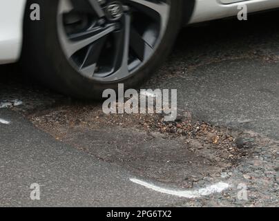 File photo dated 11/05/2018 of a car hitting a pothole. Shortfalls in pothole repair budgets among local authorities have reached a record high, according to research. Councils in England and Wales said they only received two-thirds of what they needed during the current financial year to stop local roads further deteriorating, the Annual Local Authority Road Maintenance (Alarm) survey found. Issue date: Tuesday March 21, 2023. Stock Photo