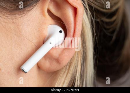 wireless white headphones in a girl's ear close-up Stock Photo