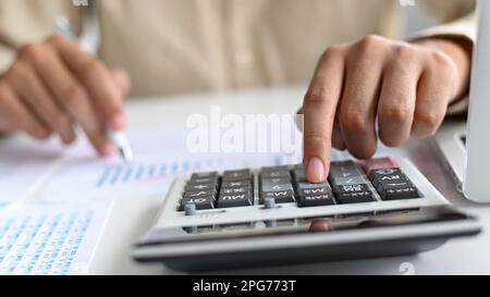 Close-up shot of Young man holding a pen and using a calculator placed in front, A man holding a pen and using a calculator. Stock Photo