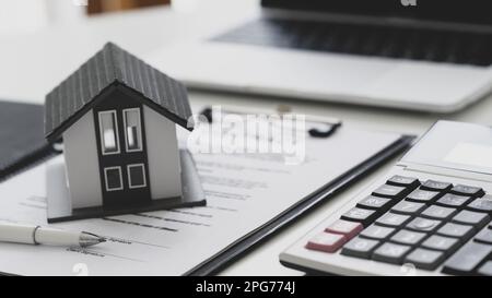 Model house put on contract documents with calculator and laptop. ,Contracting house construction concept, Top view shot. Stock Photo