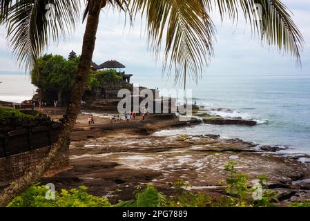 Tanah lot hindu temple seen from a palm tree on Bali in Indonesia Stock Photo