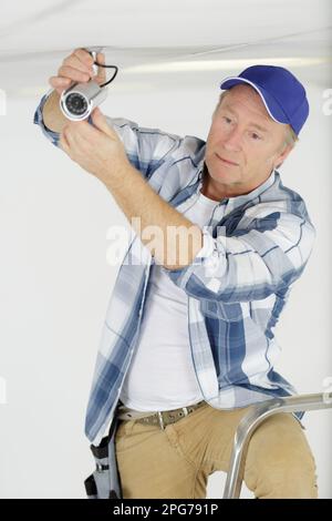 mature man mounting a cctv camera Stock Photo