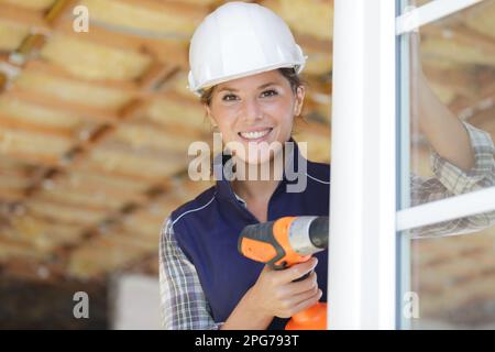 female builder using cordless drill on pvc window Stock Photo