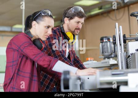 female apprentice working with engineer on cnc machinery Stock Photo