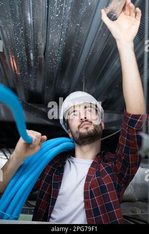 male electrician installing ventilation in ceiling Stock Photo