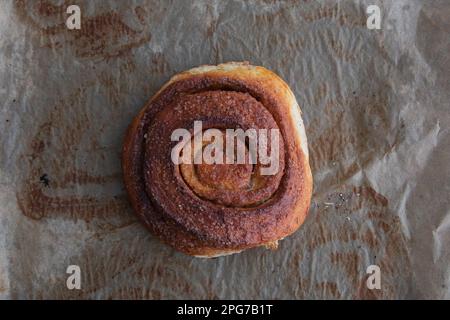 top view of homemade cinnamon bun on sheet of baking paper Stock Photo