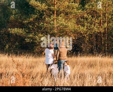 A young married couple with children is planning to build a house on a plot near the forest Stock Photo