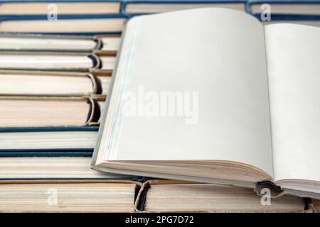 Open vintage book or notebook with blank pages lies on the background of a row of shabby books. Design mockup with copy space Stock Photo