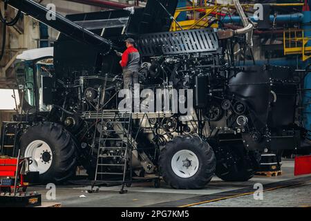 Industrial worker assembles agricultural harvester in workshop. Stock Photo