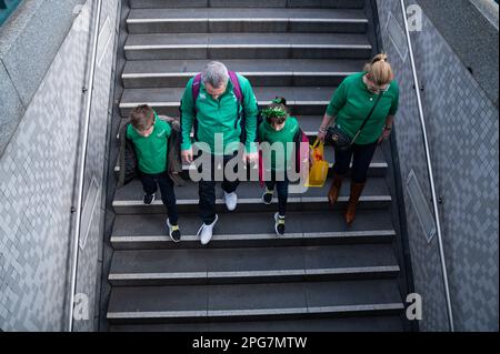 18.03.2023, Berlin, Germany, Europe - A family dressed in green to celebrate the Irish St. Patrick's Day walks down the stairs to a subway station. Stock Photo