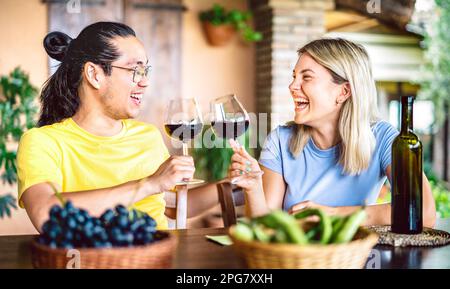 Happy couple in love toasting red wine at countryside farm house restaurant - Food and beverage life style concept with boyfriend and girlfriend Stock Photo