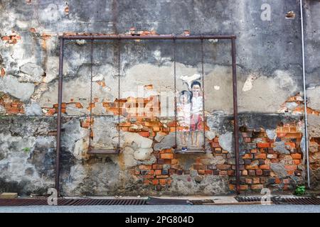 Penang, Malaysia - February 7, 2023: Street Art Brother And Sister On A Swing On A Wall In George Town On Penang Island In Malaysia. Stock Photo
