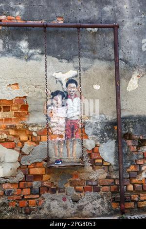 Penang, Malaysia - February 7, 2023: Street Art Brother And Sister On A Swing On A Wall Portrait In George Town On Penang Island In Malaysia. Stock Photo
