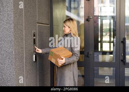 Middle aged woman pushing button of intercom Stock Photo