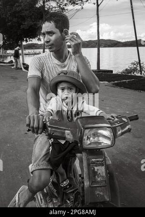 A young M'nong ethnic minority father and his son on a tatty Honda scooter in Jun Village, Lien Son, Vietnam. Stock Photo