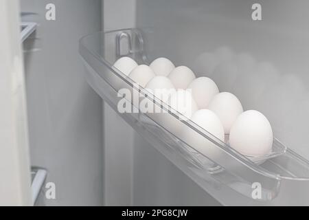 white egg lies in a cell in the refrigerator. chicken eggs are in the fridge Stock Photo