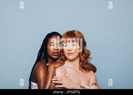 Confident women with different skin tones looking at the camera while standing together. Two young women feeling comfortable in their own skin. Body p Stock Photo