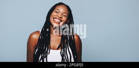 Portrait of a african woman with dreadlocks and body piercings smiling at the camera happily. Cheerful young woman feeling confident in her style. Fas Stock Photo