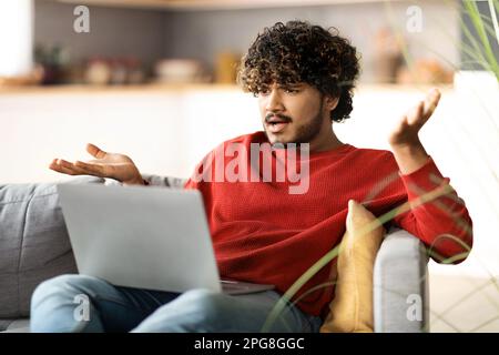 Stressed Young Indian Man Suffering Problems While Using Laptop At Home Stock Photo