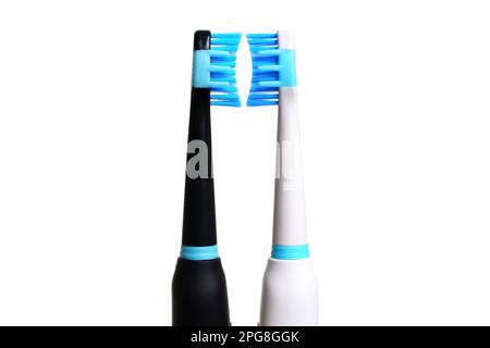 Two electric toothbrushes, one black and one white, with blue bristles that are facing each other isolated on a white background. Clean and bold backg Stock Photo