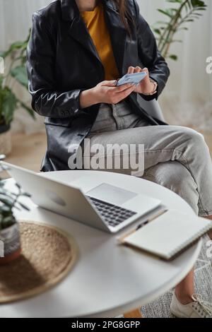 Young woman using laptop and mobile phone sitting at workplace at home, remote work Stock Photo