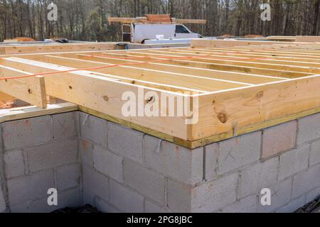 New custom home installation of wood floor joists trusses on concrete block  foundation Stock Photo - Alamy