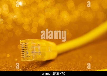 A high-resolution closeup of a yellow Ethernet cable lying on a bright yellow background Stock Photo