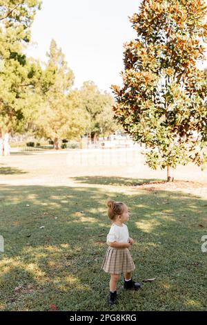 full length of baby girl in skirt and white t-shirt standing in park,stock image Stock Photo