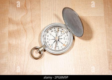 Open old vintage compass on wooden table Stock Photo