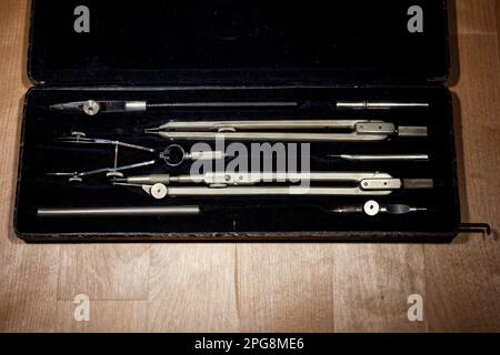 set of divider, compass inside a box for geometric construction lying on wooden table Stock Photo