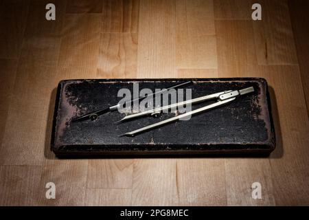 set of divider, compass inside a box for geometric construction lying on wooden table Stock Photo