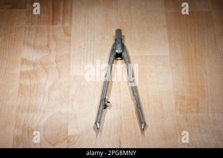 divider. compass for geometric construction lying on wooden table Stock Photo