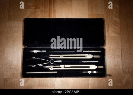 set of divider, compass inside a box for geometric construction lying on wooden table Stock Photo