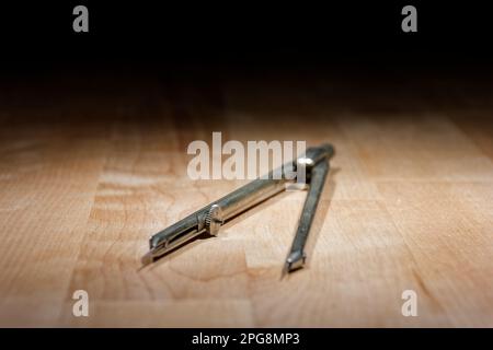 divider. compass for geometric construction lying on wooden table Stock Photo