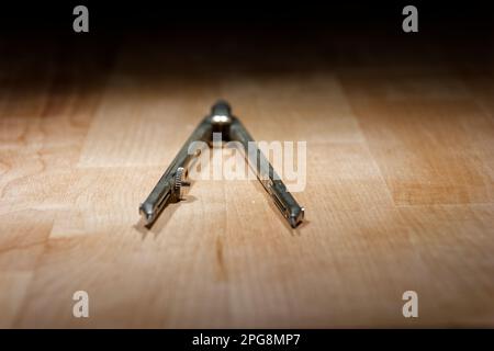 divider. compass for geometric construction lying on wooden table Stock Photo