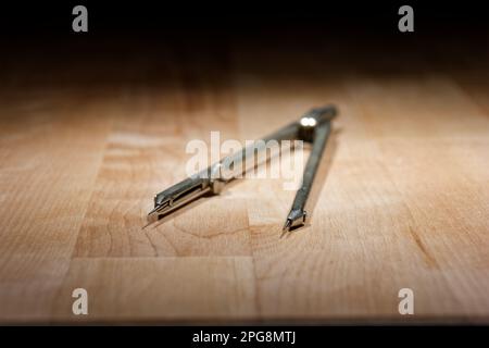 divider. compass for geometric construction lying on wooden table Stock Photo