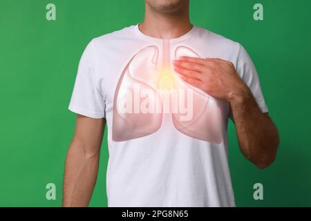 Man holding hand near chest with illustration of lungs on green background, closeup Stock Photo