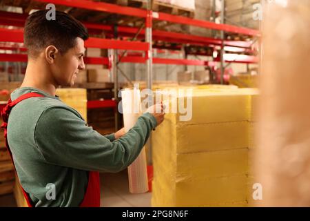Worker wrapping boxes in stretch film at warehouse Stock Photo