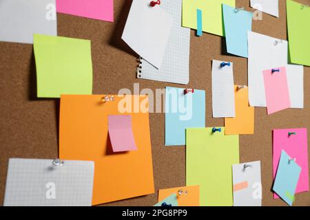 Many colorful notes pinned to cork board, closeup Stock Photo