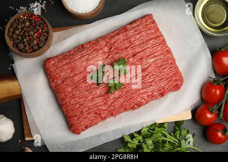 Raw fresh minced meat, tomatoes and other ingredients on black table, flat lay Stock Photo