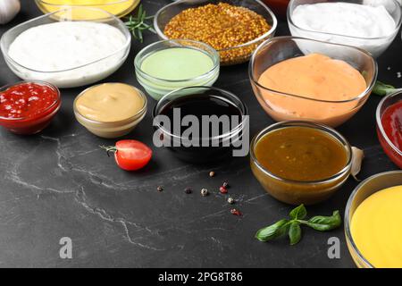 Many bowls with different sauces on black table Stock Photo