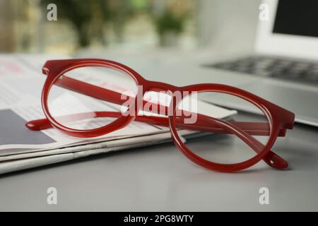 Newspaper and glasses on grey table, closeup Stock Photo